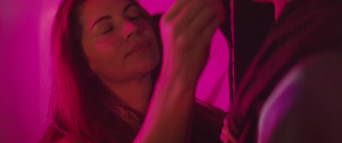 Female make up artist touches up model as patterned colored lights shine across them