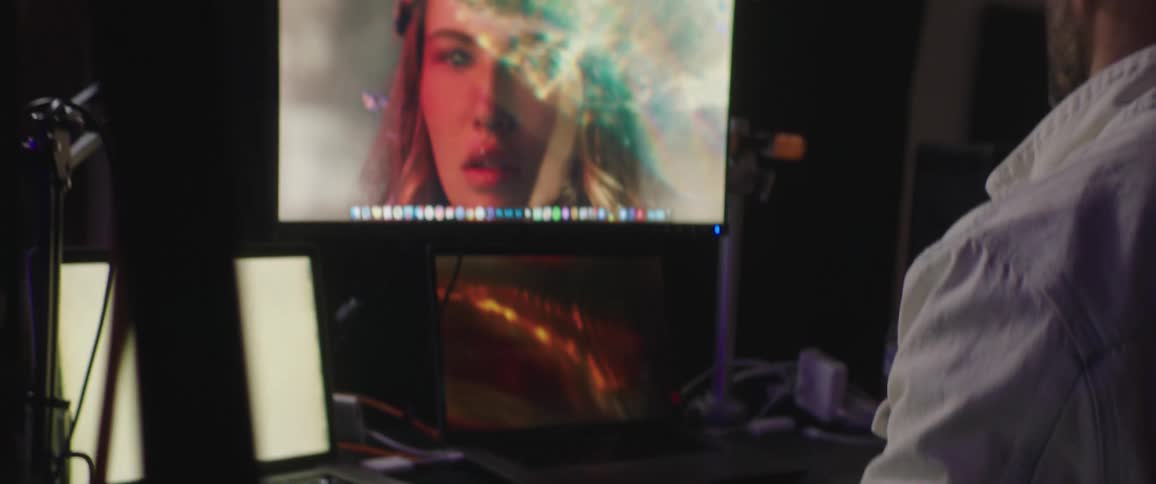 A man sits in front of a large computer screen in a darkened room