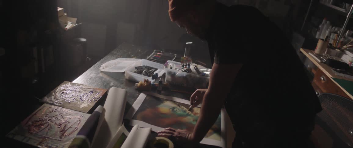 A man painting on a canvas on a table