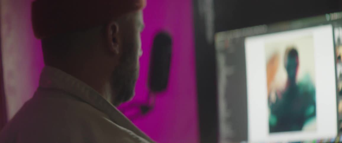 Man wearing a toque looks at photos on a monitor