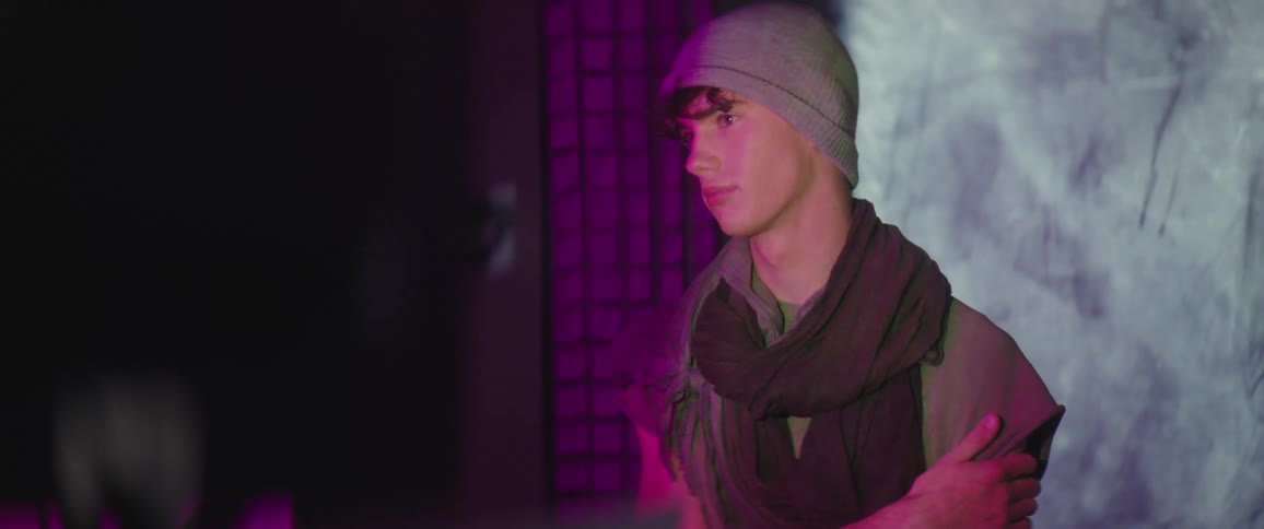 A model poses in a hat and scarf i front of an image changing screen