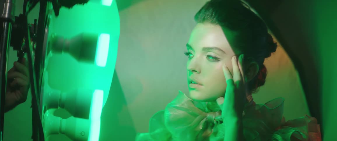 A photographer takes a photo of a woman at a photo shoot in a room with lights changing from green to blue