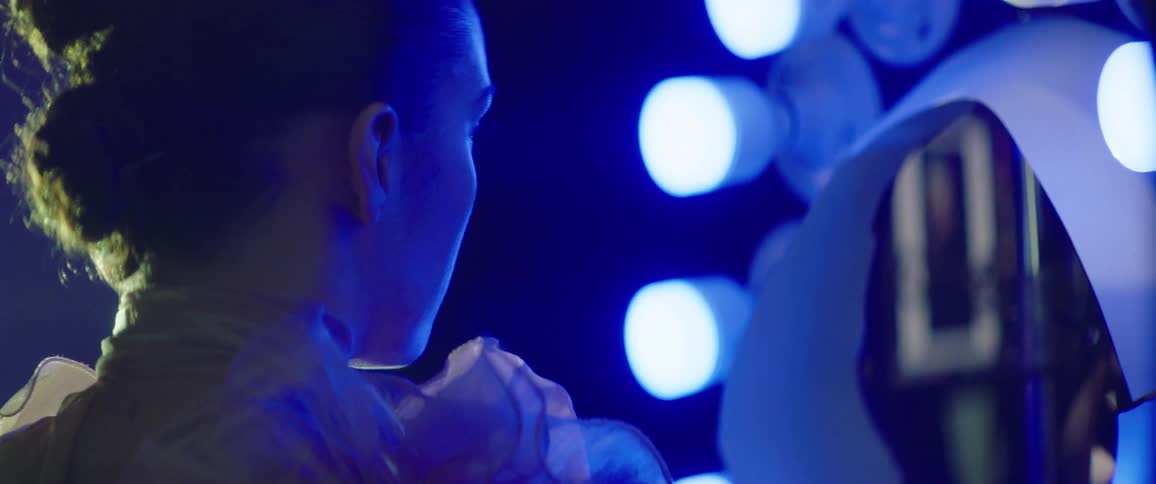 A female model stands and poses while illuminated with blue lighting