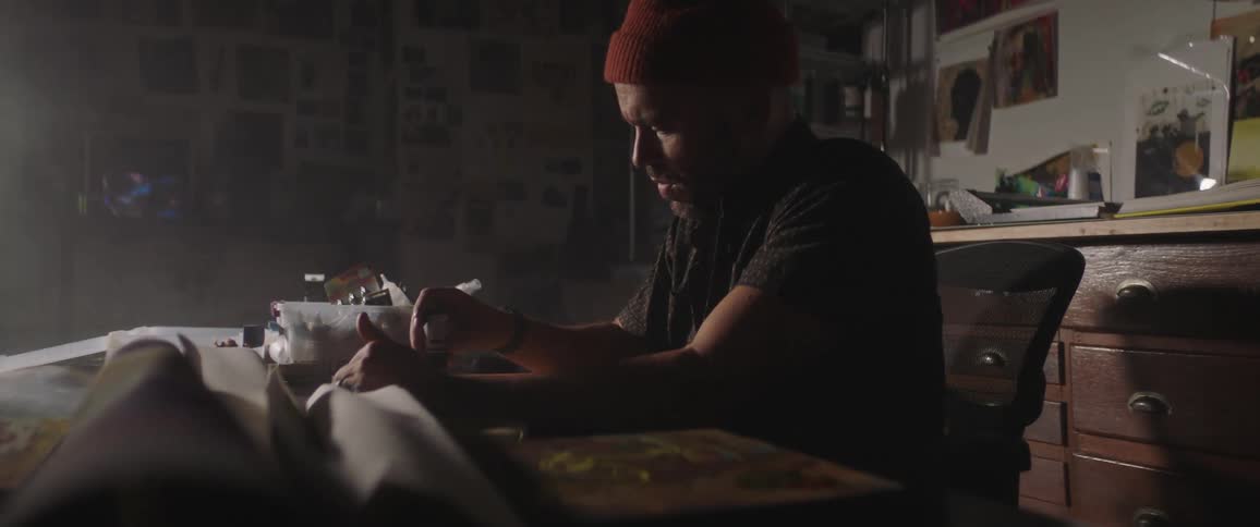 Artist painting with oil on a table inside a dimly lit studio