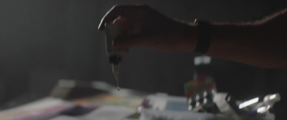 A person in a room applying drops of liquid on a paper on a table