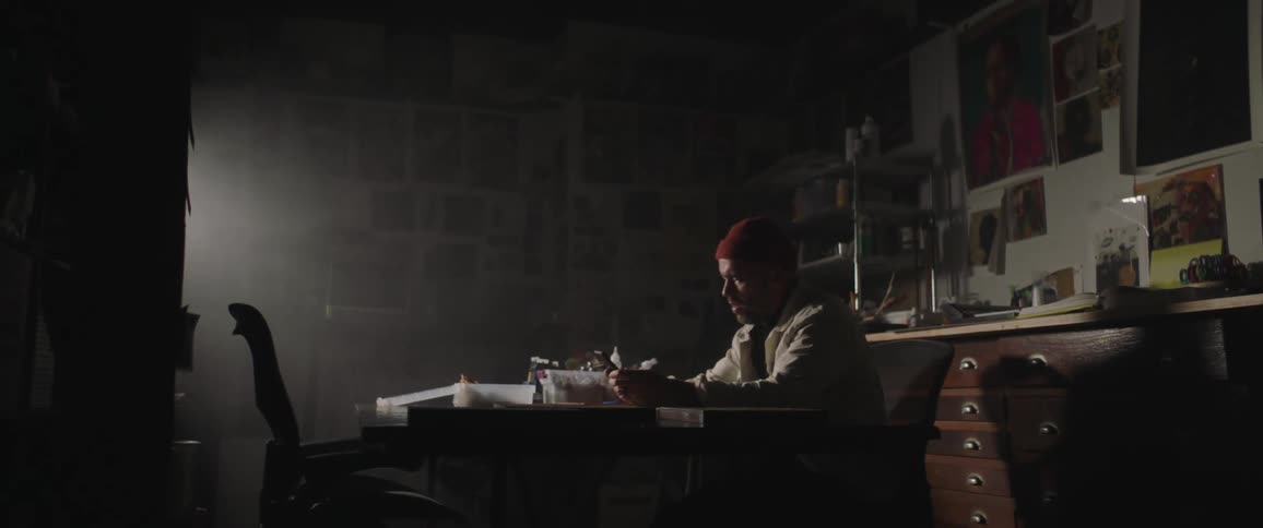 A man sits at his desk with painting equipment