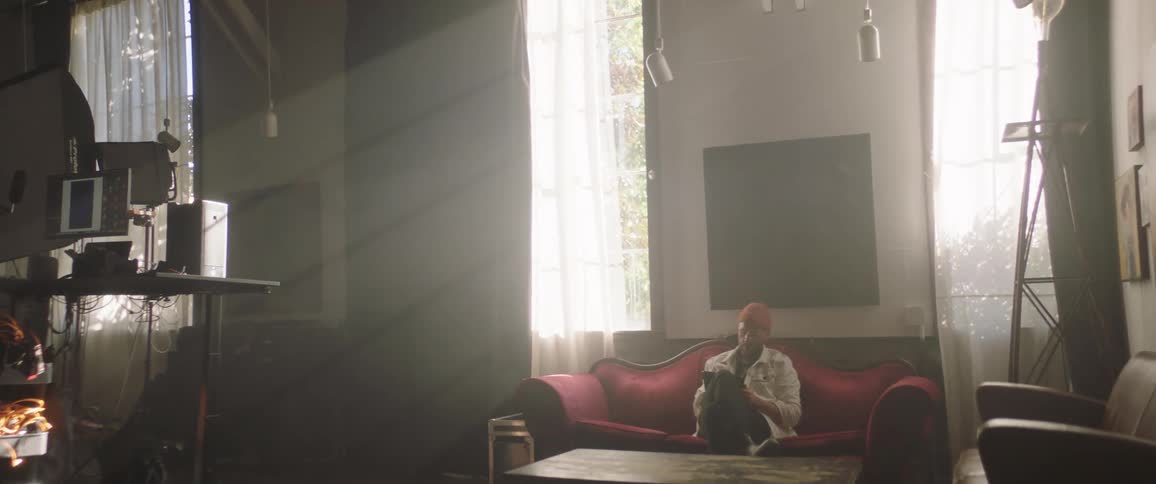Man wearing a toque holds a tablet while sitting on a red sofa