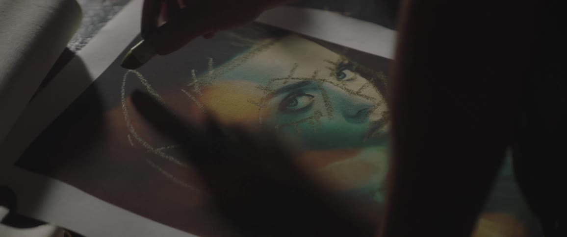 A hand sketching on an unfinished piece of art on top of a table