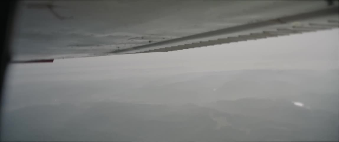 An aircraft with a landscape with hills with the sky and clouds in the background