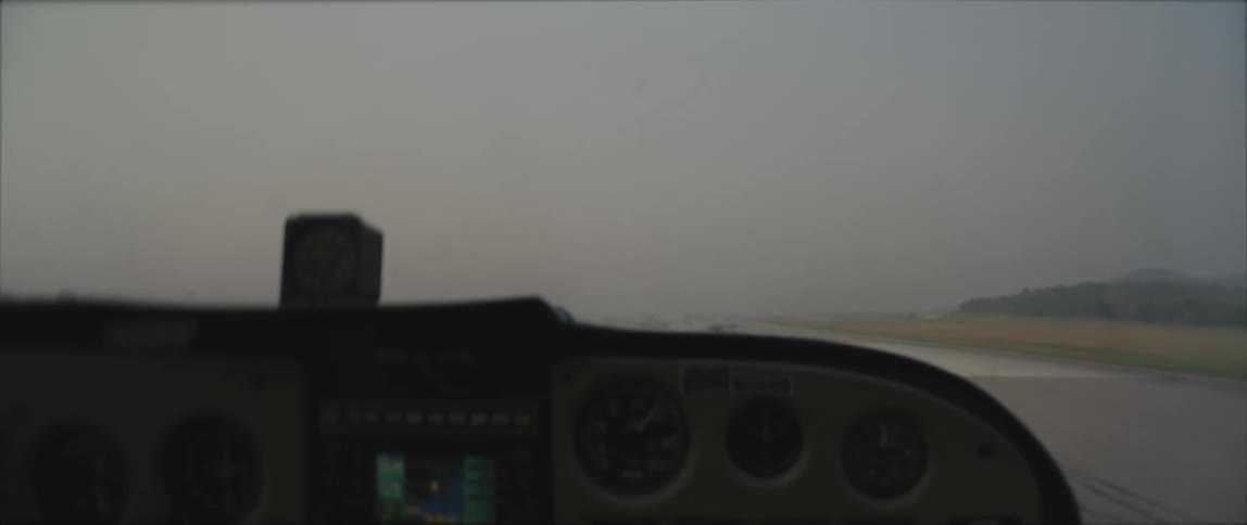 A small airplane travels down a runway on a cloudy day