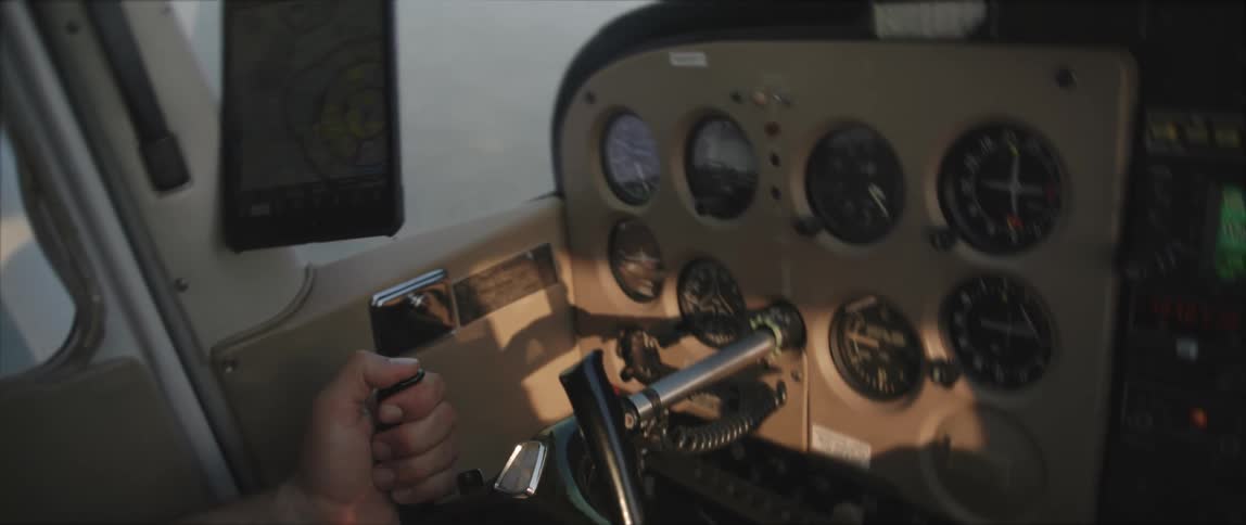 A hand on an aircraft yoke in a small plane cockpit