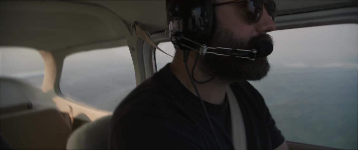 A pilot glances out of the window at the landscape below as he pilots a plane through the sky