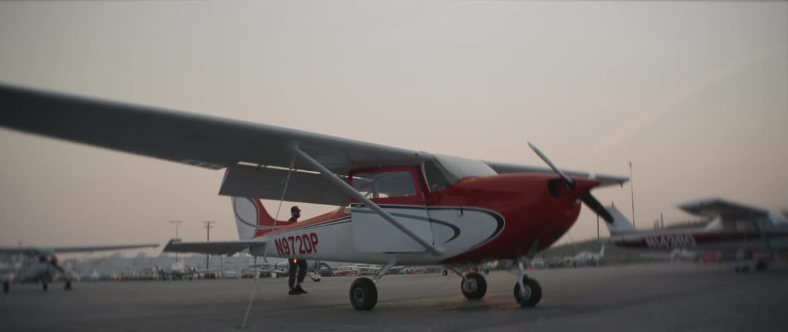 A man walks to a small airplane in an airport