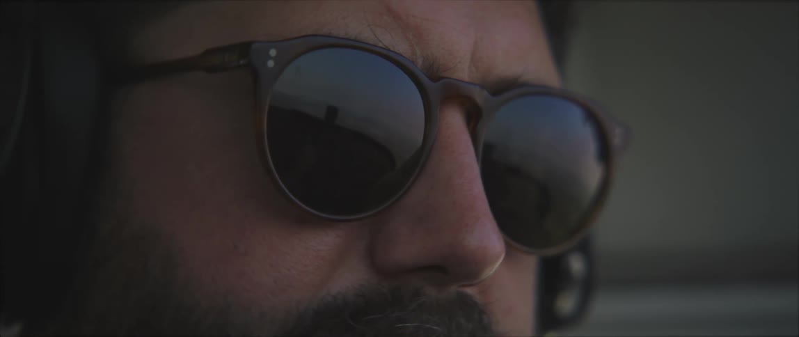 The sky and propeller are reflected in a pilots sunglasses