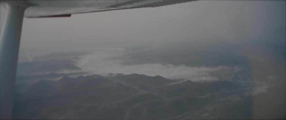 An aircraft with a landscape with hills the sky and clouds in the background