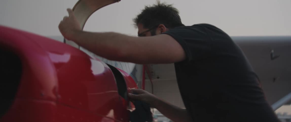 A man is at an airport and wearing sunglasses at dusk