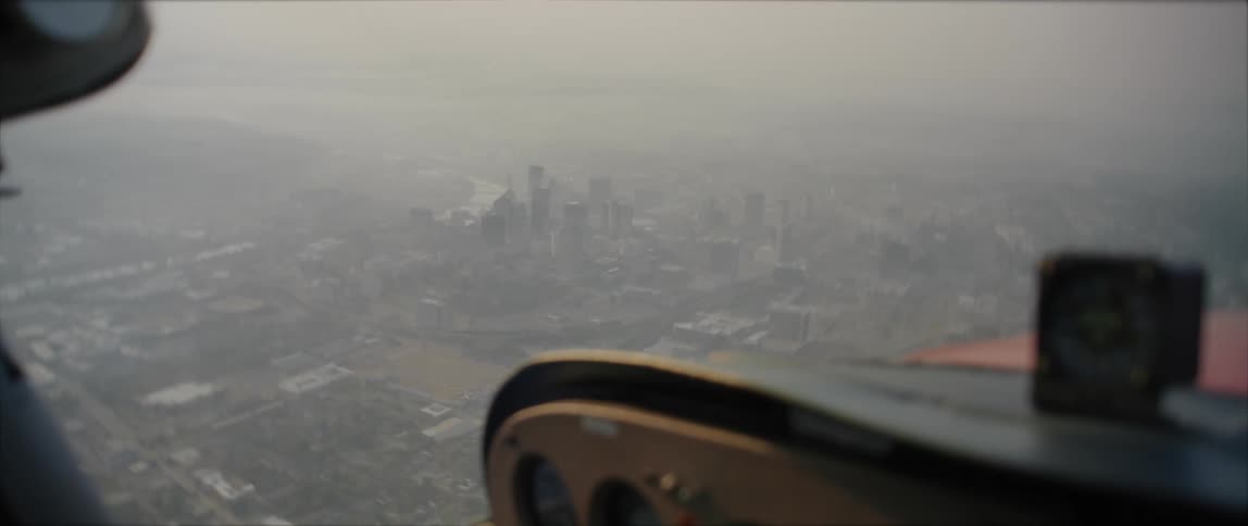 Aerial view of a large city with a tower block in the distance on a misty day