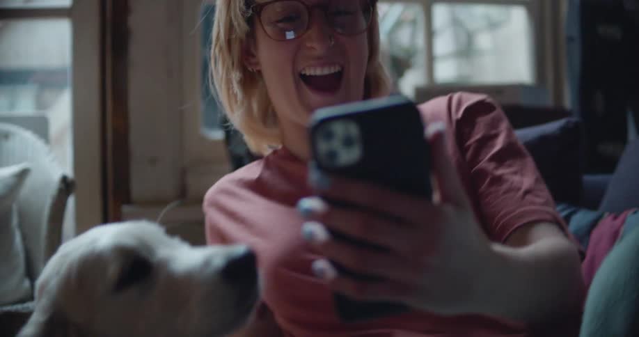 A woman laughs during a video call when she puts the cell phone in front of her dog