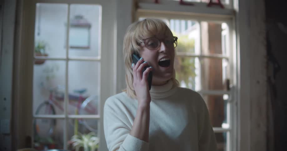 A woman laughs while having a conversation on a cell phone