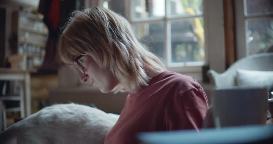 Blonde woman reading while sitting on the living room drinking coffee