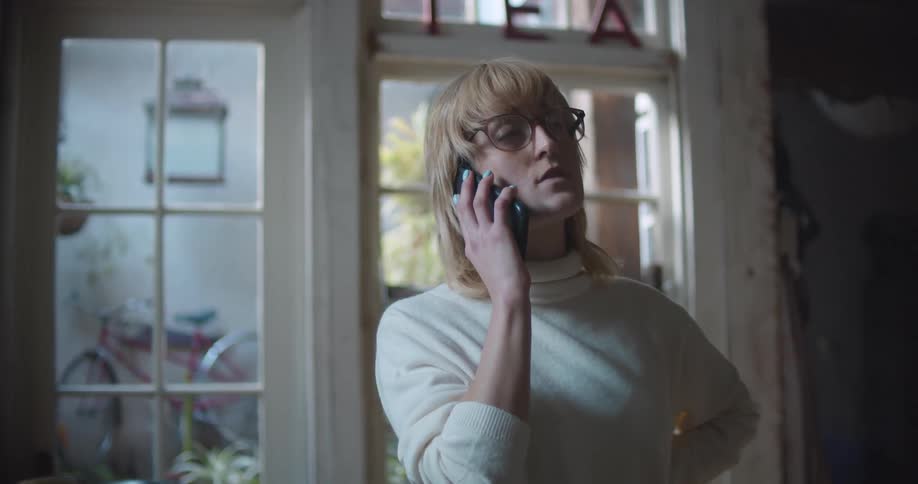 A woman looks nervous talking on a cell phone