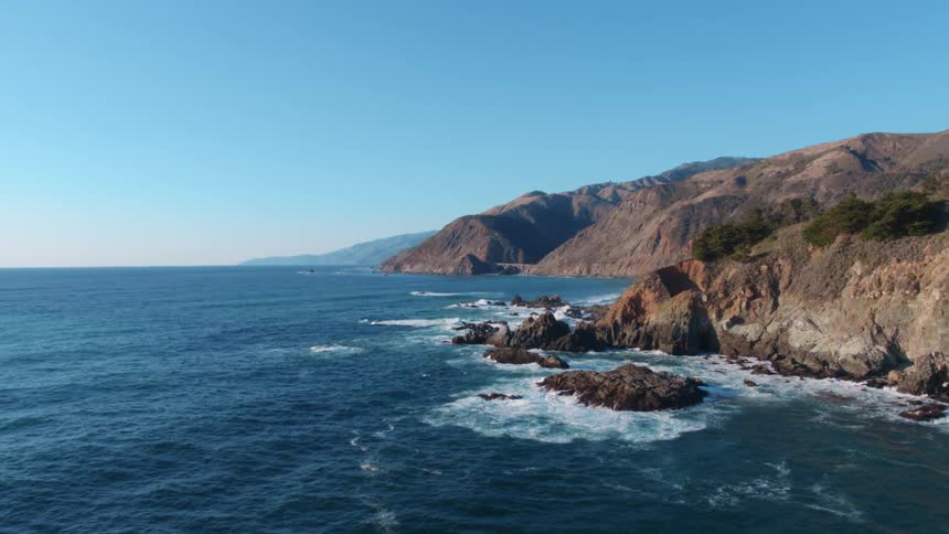 A rocky shoreline has waves crashing into it