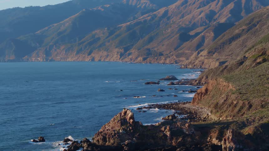 The waves are crashing against the rocky shore line
