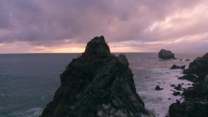 Dark clouds are hanging over a rugged coast near sunset
