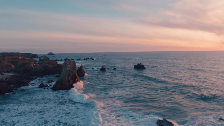 A rocky coast with waves with the ocean the sky and clouds in the background