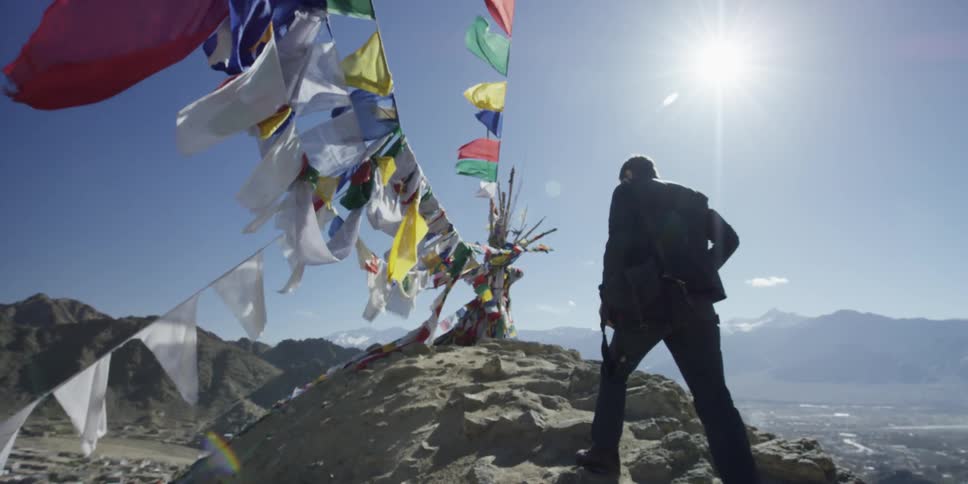 A man walks uphill past some flags