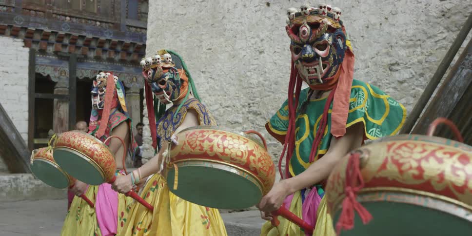 Four people in costumes beat on drums