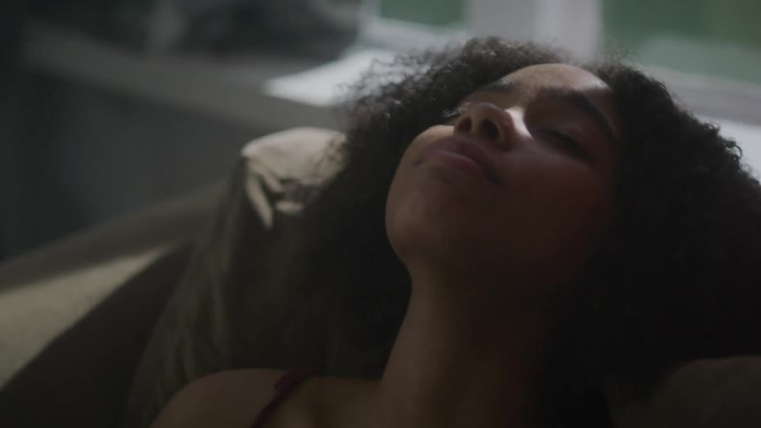 Woman sits back on couch resting head on cushions