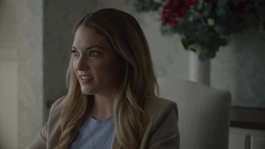 A woman is sitting and smiling as she talks
