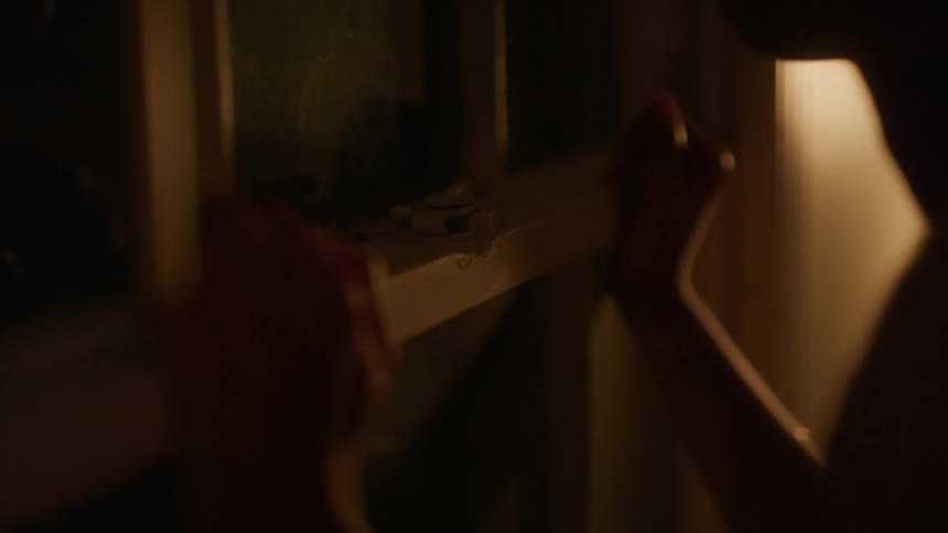 Woman undoes the latch on a window then opens the window