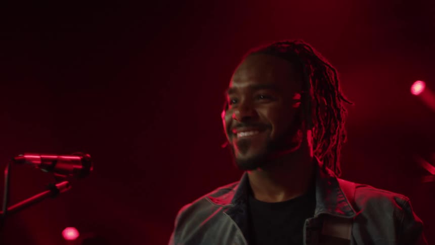 A guitarist performs on stage alongside other musicians