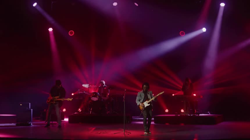 A band plays onstage as neon light beams shine down