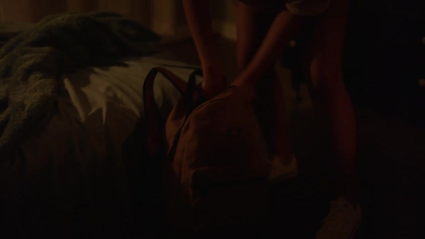 A woman shoving clothes into a bag