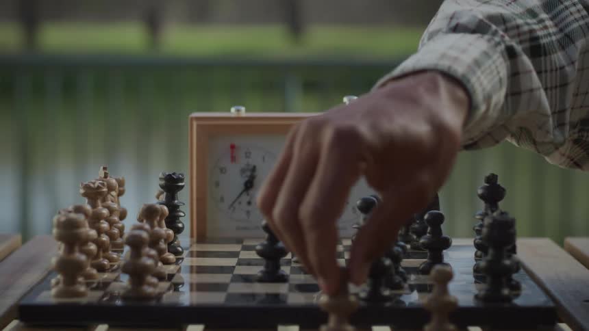 Chess player makes a chess move then pushes the button on the timer