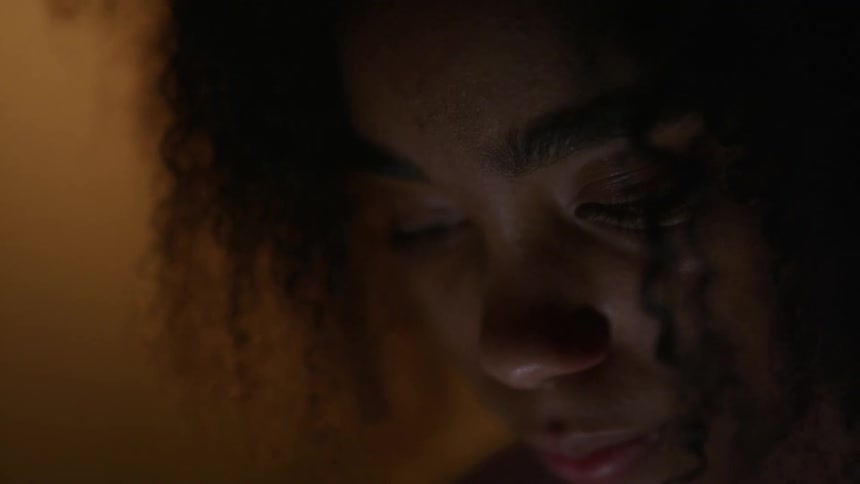 Woman with curly hair looks concentrates downward pursing her lips
