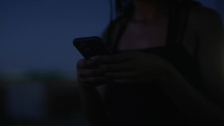 A woman standing and using a smart phone with a vehicle the sky and the moon in the background
