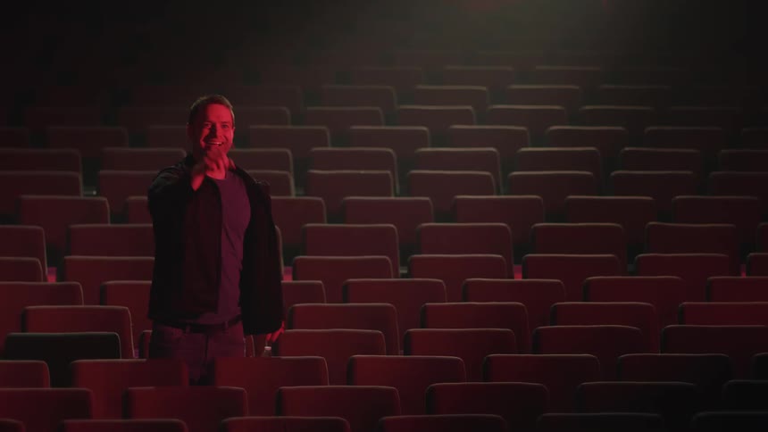 A man cheers and claps as he stands alone in an empty venue