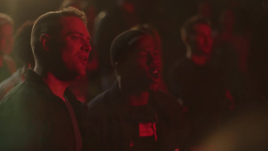 Two men in a crowd dancing and smiling with people in the background