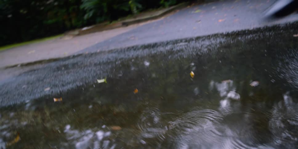 A child wearing rain boots runs and jumps into a puddle