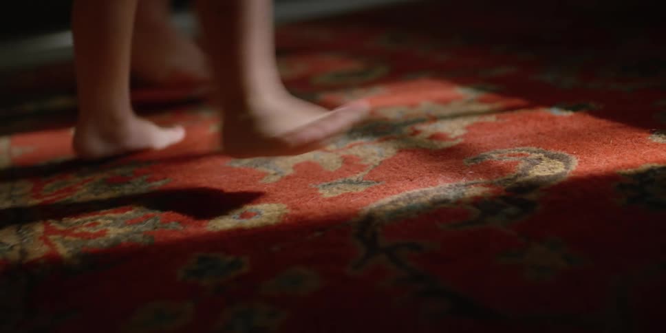 A barefoot toddler stomping on an indoor rug