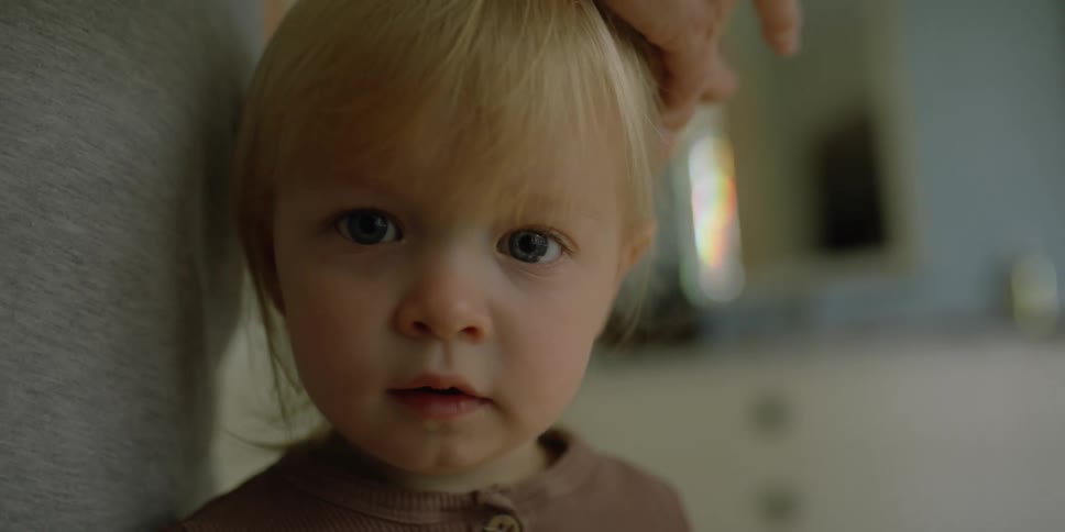 A little girl stands still as grandma puts her hair into ponytails