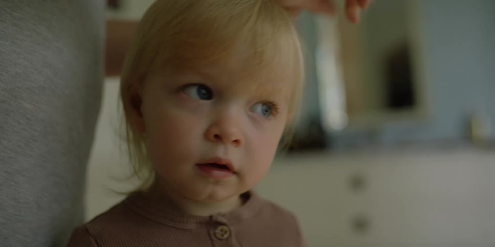 A little girl holds a comb as her hair is put into a ponytail