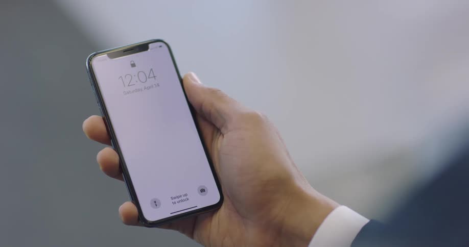 A man holds a cell phone in his hand and looks at the time on it