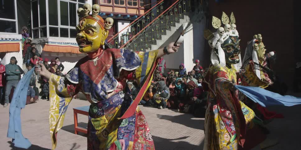 Masked people dance in front of a crowd