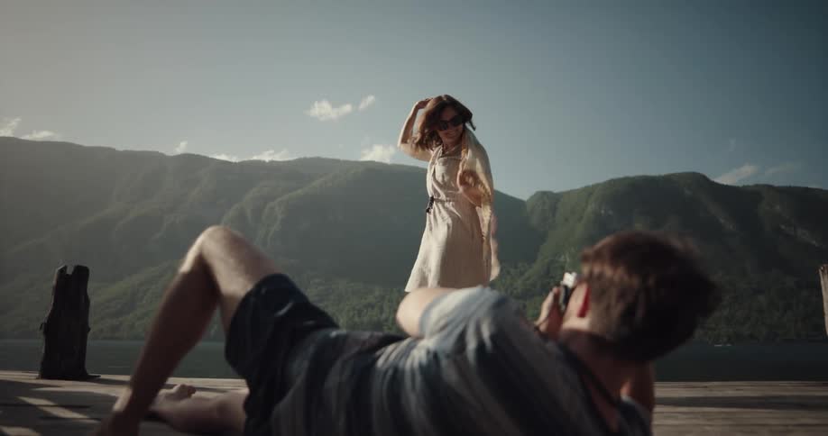 A man photographing a woman dancing outside