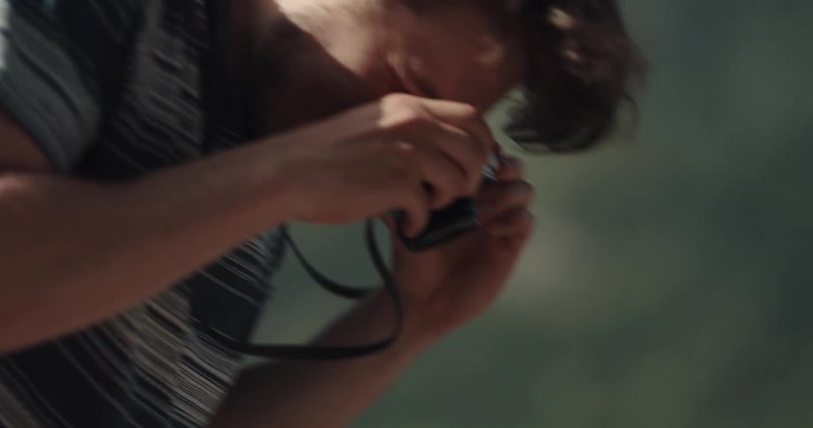 Man takes pictures of woman leaning down to kiss her as water passes by in background